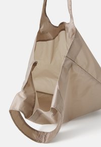 Beige tote bag lavet af letvægtigt, struktureret stof. Har brede, afrundede håndtag og en åben top. Indvendigt har den et fint gittermønster.