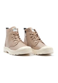 Bottes hautes en cuir beige avec semelles en caoutchouc blanches, dotées de lacets, d'une fermeture éclair sur le côté et d'un patch logo sur la languette.