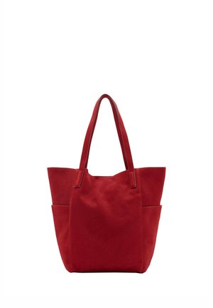 Red suede tote bag with two long handles and side pockets, standing upright on a plain white background.