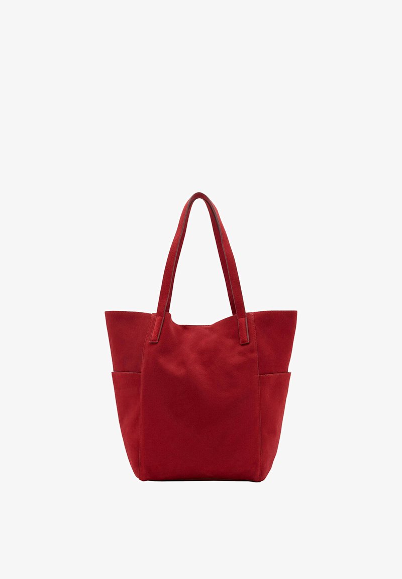 Sac cabas en daim rouge avec deux longues anses et des poches latérales, debout sur un fond blanc uni.