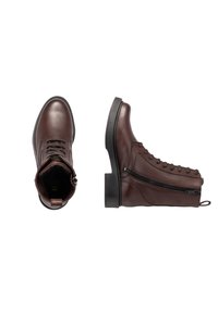 Une paire de bottines en cuir marron foncé avec fermeture éclair sur le côté et lacets, l'une montrée de dessus et l'autre en vue latérale sur fond blanc.