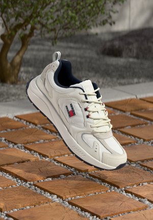 Adidași albi pentru alergare cu panouri texturate, șireturi subțiri, accente bleumarin și un logo cu dungi roșii, albe și albastre. Design al unei talpa ușoară.