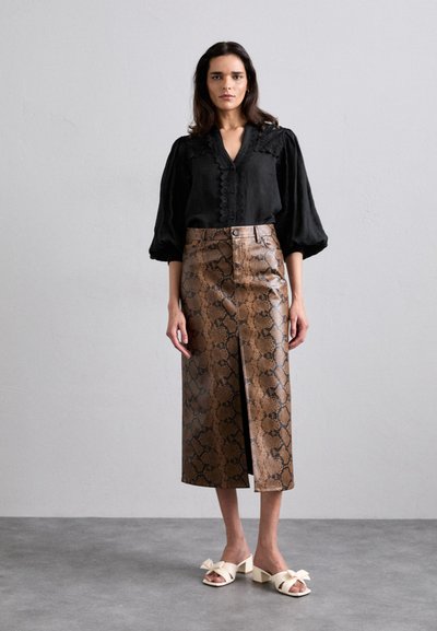 Zwarte blouse met pofmouwen en knoopdetails; bruin nep-slangenleer midi-rok met een voorknipoog; witte blokhak sandalen.