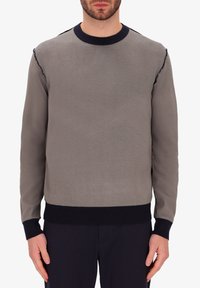 Felpa grigia a maglia con collo rotondo, caratterizzata da un corpo texturizzato, polsini e orlo a coste blu, e dettagli sfrangiati sulle spalle.