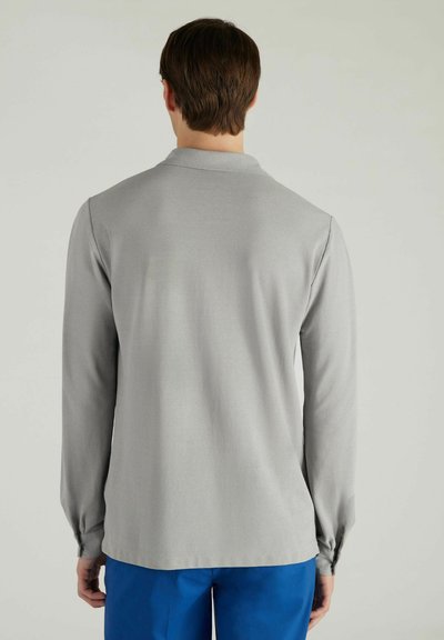 Grijze halflange mouwen poloshirt met een gladde textuur en een subtiele kraag; gecombineerd met blauwe broek. Geen zichtbare patronen of hardwaredetails.