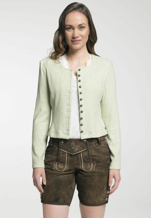 Veste côtelée vert clair avec fermeture à boutons et col rond, associée à un short marron avec des détails brodés et des boutons sur les côtés.