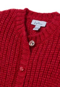 Gilet en tricot rouge pour bébé avec un motif texturé, deux boutons et une étiquette blanche portant l'inscription "fagottino", taille 12-18 mois.