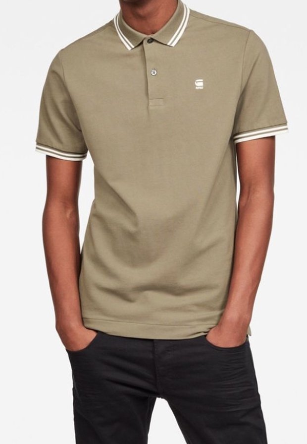 Polo beige avec col et poignets à rayures blanches, manches courtes, un petit logo sur la poitrine et une coupe classique. Texture en coton doux.