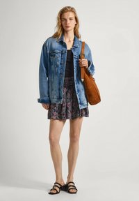 Denim jakna, črna top z naramnicami, cvetlična krila, rjava torba čez ramo in črne sandale z več trakovi. Mehak material in sproščen videz.
