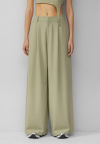 Šviesiai žali plati kelnės, pagamintos iš lygaus audinio. Turi pritaikytą siluetą su priekinėmis klostėmis ir kvadratiniu sagties uždarymu.