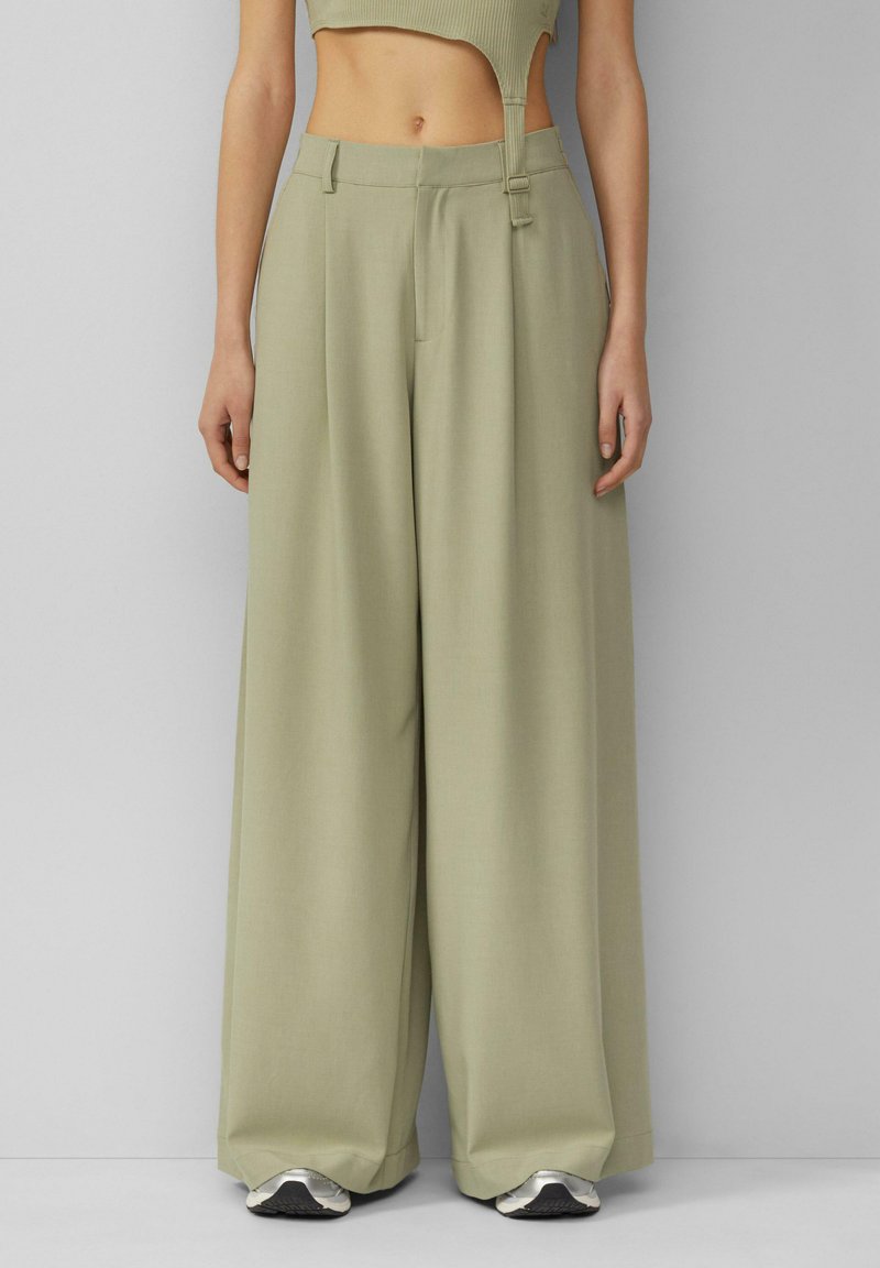 Šviesiai žali plati kelnės, pagamintos iš lygaus audinio. Turi pritaikytą siluetą su priekinėmis klostėmis ir kvadratiniu sagties uždarymu.