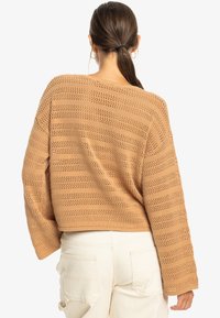 Cropped, knitted sweater in light brown with openwork stripe design and loose sleeves. Details include a rounded neckline and ribbed hem.
