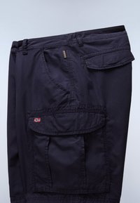 Pantalon cargo bleu marine foncé avec plusieurs poches, dont une poche à rabat ornée d'un petit patch drapeau norvégien.