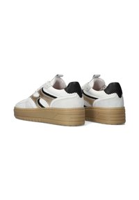 Lage sneakers met een witte suède bovenkant, zwarte en beige accenten, en een dikke beige zool. Gladde textuur met contrasterende stiksels.