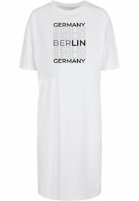 Bílé šaty ve tvaru trička s potisky "NĚMECKO" a "BERLÍN" v různých odstínech šedé. Neformální design s krátkými rukávy a volným střihem.
