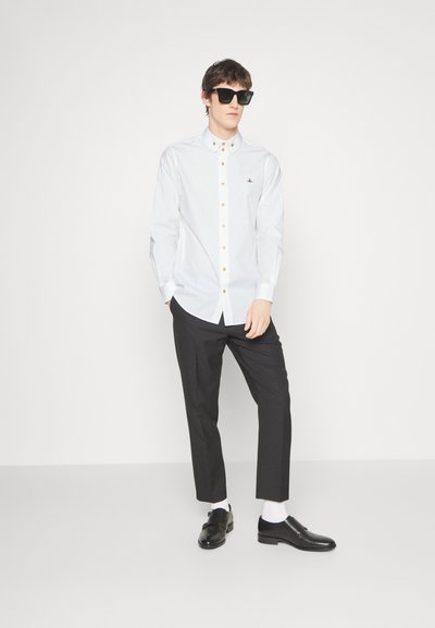 White button-up shirt with golden buttons, black trousers, black shoes, and sunglasses. Slim fit with a casual design.