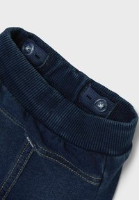 Jeans azul marino con una cinturilla acanalada, que cuentan con dos botones y costuras en amarillo que contrastan a lo largo de las costuras. Textura suave.