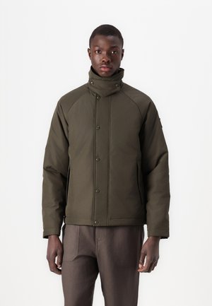 Veste isolante verte olive avec un col haut, des boutons-pression et des manches raglan. Le tissu semble lisse avec des accents minimes.