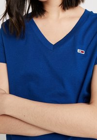 Blue cotton short-sleeve V-neck t-shirt with a small logo accent on the left chest. Soft texture and relaxed fit.