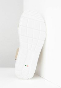 Beige sandal featuring a textured, white rubber sole with a patterned tread and a small Italian flag accent near the heel.