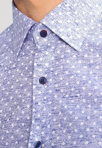 Light blue patterned shirt featuring a texture of diagonal lines and small white dots, with dark blue buttons and a classic collar.