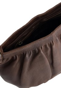 Brown leather handbag with a textured finish, featuring a gathered design and a zippered top closure. Interior is lined with dark fabric.