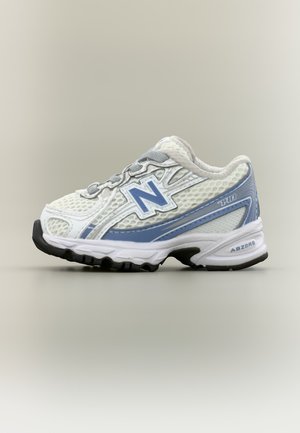 Belo in svetlo modro tekaško copato New Balance z mrežastim zgornjim delom, blaženo podplatom in črnim profilom, prikazana od zunanje strani.