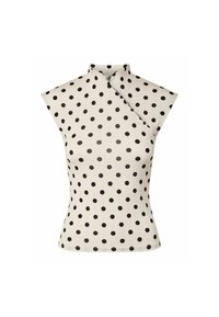 Haut blanc sans manches à pois noirs, col haut et fermeture asymétrique boutonnée sur la poitrine.