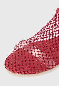 Red open-toe shoe with a netted mesh upper featuring black accents, curved shape, and a glossy transparent section at the toe.
