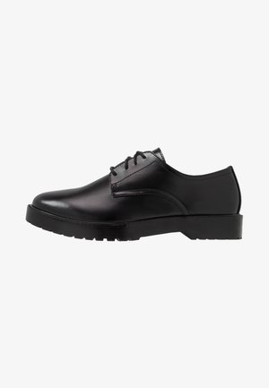 Zwarte leren nette schoen met een gladde afwerking, ronde teen, vetersluiting en een gestructureerde rubberen zool voor grip. Hoekige hak.