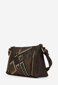 Bolso de hombro de cuero marrón con un diseño de patchwork geométrico, tachuelas, dos cremalleras y correa ajustable. Las superficies texturizadas varían en acabado.