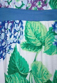 Materiał w kwiatowy wzór z żywymi zielonymi liśćmi i niebieskimi kwiatami na białym tle, z jednolitą niebieską talią.