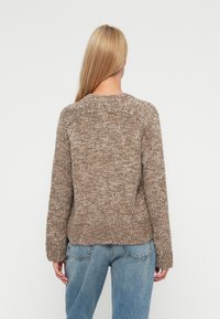 Kötött pulóver texturált, bézs-barna árnyalatban, kerek nyakkivágással és hosszú ujjakkal, laza szabással és bordázott aljjal.