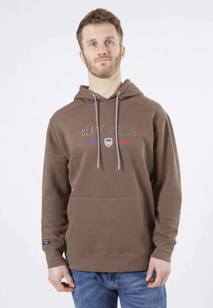 Sweat à capuche marron avec une poche frontale, arborant le texte brodé "BLACK WELLS" en blanc avec des rayures rouges et bleues. Capuche avec cordon, tissu doux.