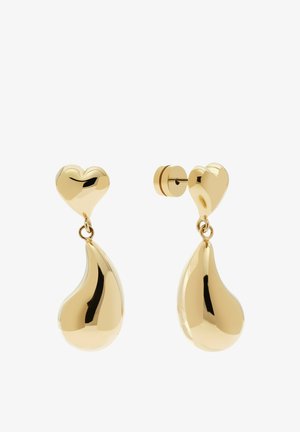 Boucles d'oreilles clous en métal doré avec des têtes en forme de cœur et des pendentifs abstraits en forme de goutte suspendus sur un fond blanc.