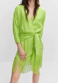 Limonengrünes Wickelkleid mit fransigem Saum, langen Ärmeln und gebundenem Taillenband. Weiche Textur mit dezenten Mustern.