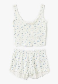 Conjunto de pijama de algodón que incluye un top corto sin mangas y pantalones cortos. Blanco con estampado floral azul, tejido acanalado texturizado y bordes con volantes.