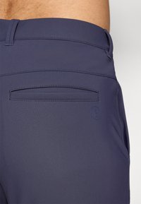 Navyblauwe shorts met een soepele textuur, voorzien van een achterzak en een klein logo aan de zijkant, ontworpen met strakke lijnen en minimale naden.