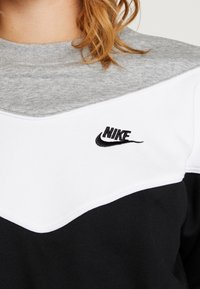 Svart och vit Nike-tröja med en grå texturerad övre del, ett chevron-mönster och en broderad logotyp på bröstet.