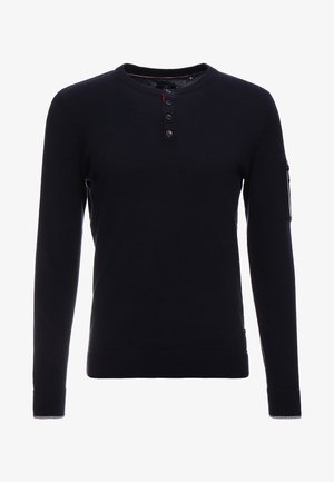 Pull henley noir à manches longues avec col rond côtelé, patte à trois boutons, poignets et ourlet côtelés, et poche zippée sur la manche gauche.