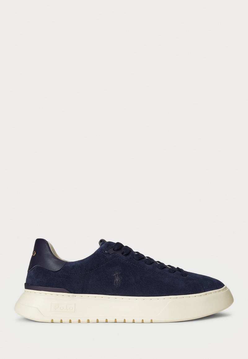 Sötétkék velúr alacsony szárú sneaker, textúrázott felülettel, gumitalppal és azonos színű fűzőkkel, kis logóval az oldalon és a sarokon.