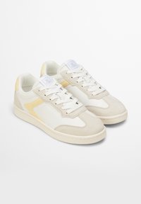 Sneaker beige e bianche con finitura in pelle liscia e scamosciata, caratterizzate da dettagli gialli, punta rotonda e lacci bianchi.