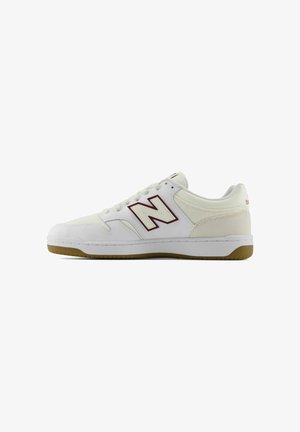 Zapatilla blanca de perfil bajo con detalles en beige, suela de goma y logo "N" con contorno granate en el lateral, presentada sobre un fondo blanco.