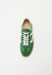Tenisi din suede verde cu dungi albe, vârful rotund și interior din piele bej. Caracteristici: șireturi albe și talpă din cauciuc maro deschis.