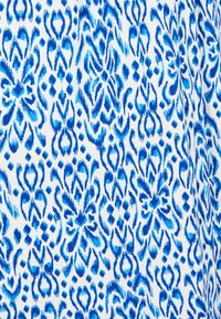Tessuto blu e bianco con motivi intricati e vorticosi e forme geometriche in diverse sfumature di blu. Texture liscia.