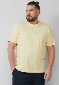 Korte mouwen gele T-shirt van zachte katoen, met een ronde hals en een klein logo op de borst. Geen opvallende patronen.