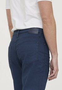 Navy blauwe katoen broek met een slim fit, voorzien van achterzakken, subtiele stiksels en een leren merklabel op de tailleband.