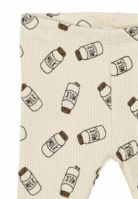 Ribbade beige leggings med ett upprepande mönster av mjölkflaskor i svart och brunt. Elastisk midja för säker passform.