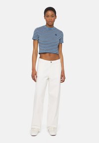 Camiseta recortada a rayas azules y blancas con cuello redondo, combinada con pantalones anchos blancos de cintura alta y zapatillas blancas.