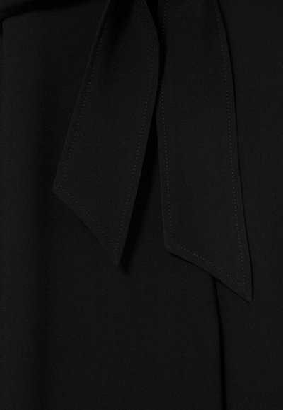 Tissu de blouse noire avec une texture lisse et un nœud au niveau du col. Présentant des lignes épurées et des détails de couture précis.